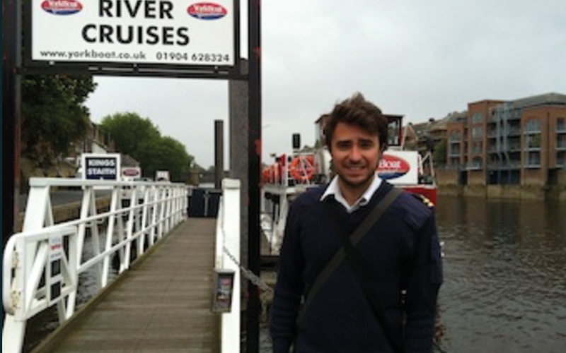 Man taking photo next to York river cruises sign